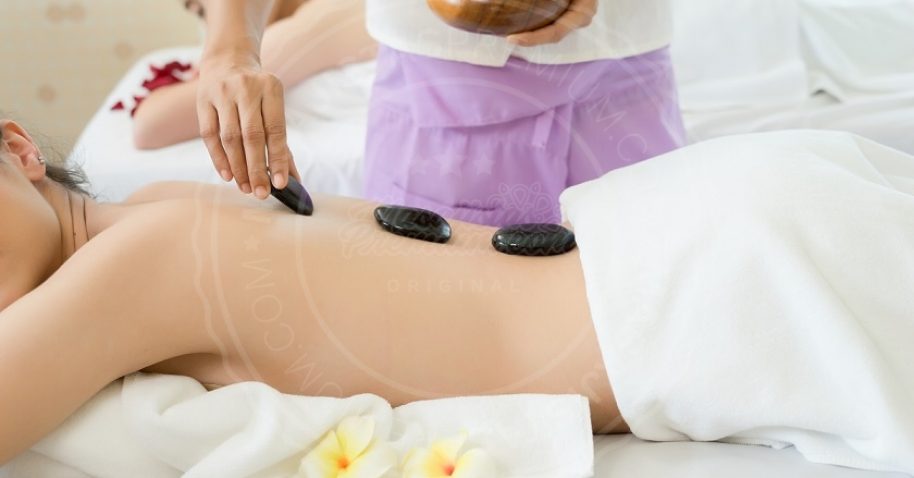 Young beautiful woman getting hot stone spa treatment.